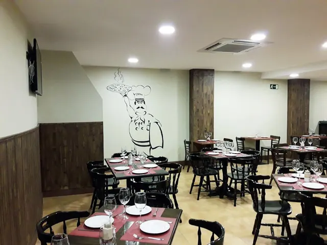 Comedor de la pizzería con zócalo de madera oscura y paredes claras