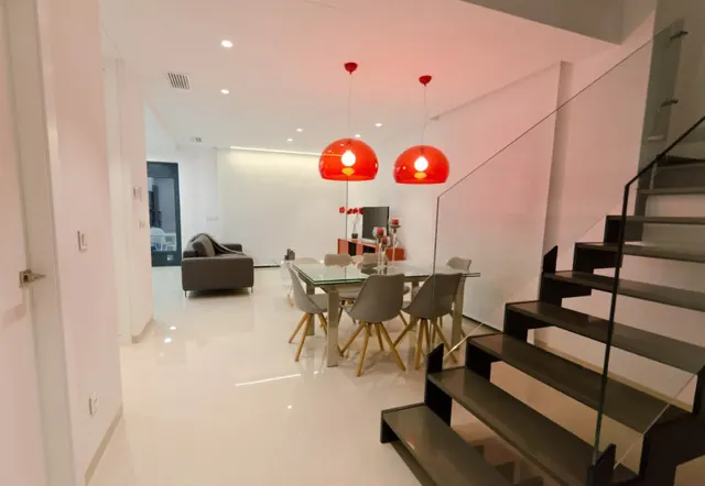 Salón comedor con escalera y paredes en blanco mate