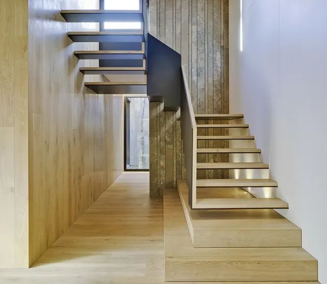 Escalera volada de madera junto a paneles verticales