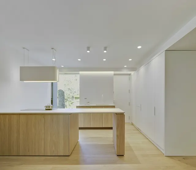 Cocina con isla de madera y armarios lacados en blanco